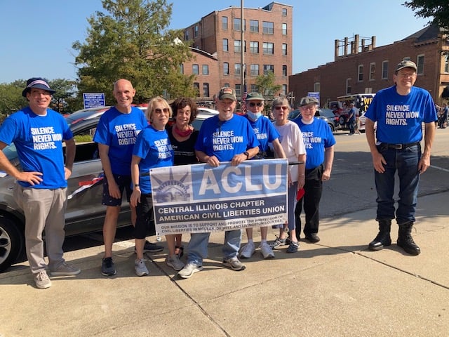 A group of members of the ACLU of Central Illinois pose for a picture during a parade.